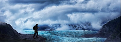 Imagen de una persona sosteniendo la cámara en un entorno montañoso salvaje con niebla, nubes y hielo glacial